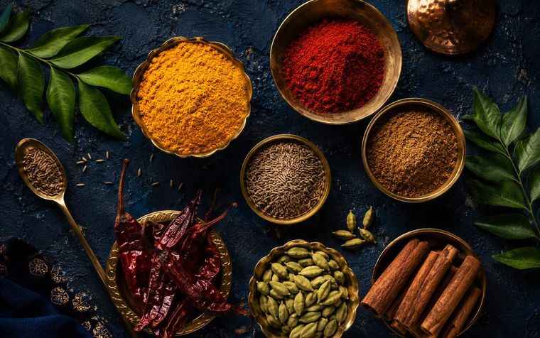 Brass bowls of freshly ground Indian spices — turmeric, chilli, garam masala, cumin, cardamom and cinnamon